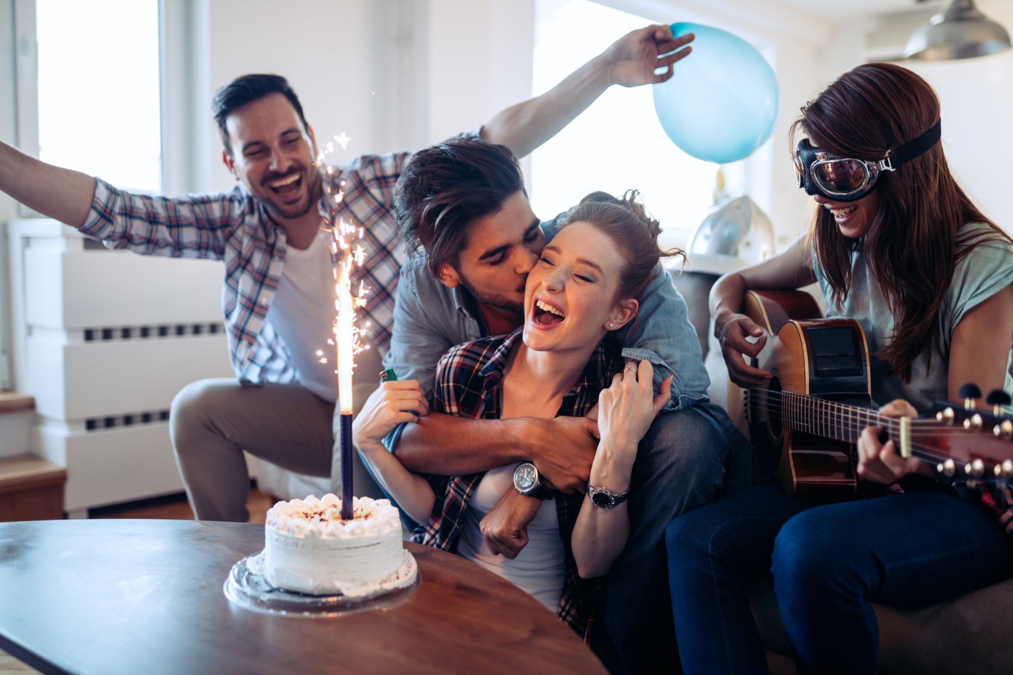 Friends celebrating a birthday with cake, sparkler and acoustic guitar — singing a personalised birthday song with the birthday person's name