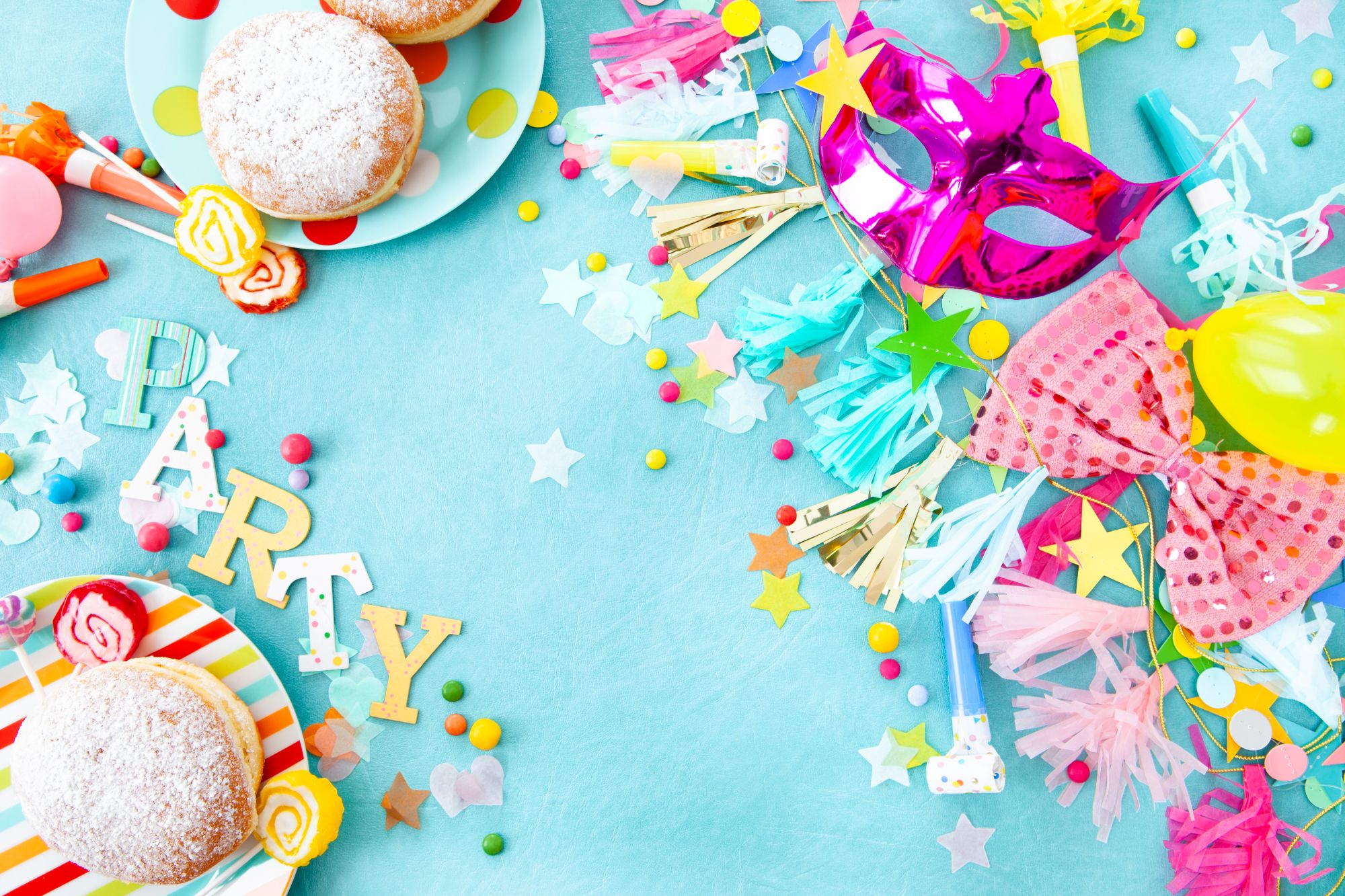 Colourful birthday party flat lay with PARTY letters, donuts, mask and streamers